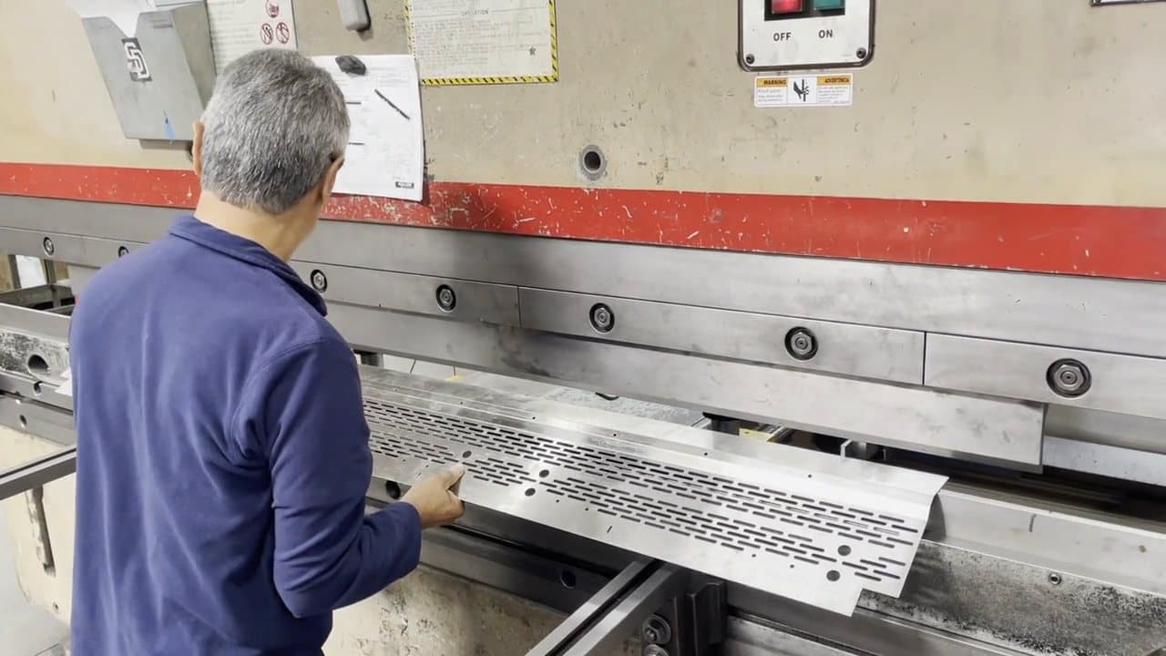 Experienced operator aligning a part against the press brake backgauge